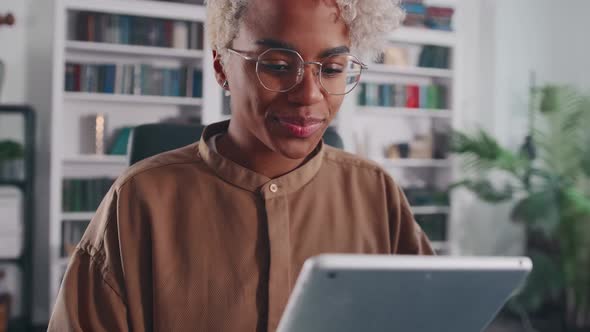 Young Successful African American Woman Entrepreneur Uses Tablet in Home Office