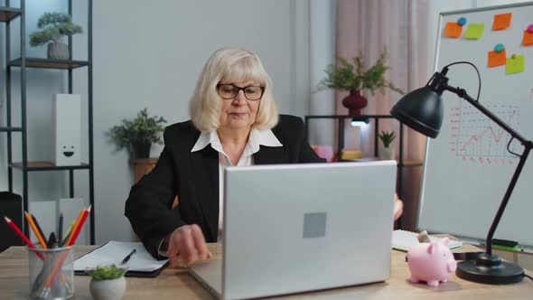 Smiling Mature Business Woman Sits at Workplace Office Desk Opening Laptop Computer Start Working