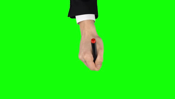 Male Hand in a Black Jacket and White Shirt with Red Marker Is Writing on Green Screen Background