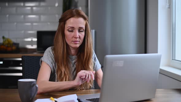 A Young Woman Works at Home with a Laptop