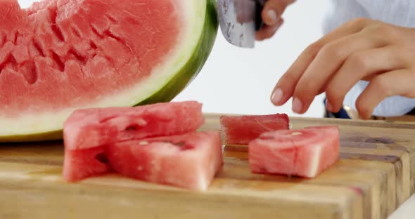 Mid-section of woman cutting fruits on chopping board against white background