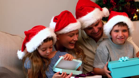 Happy young family opening christmas presents on couch