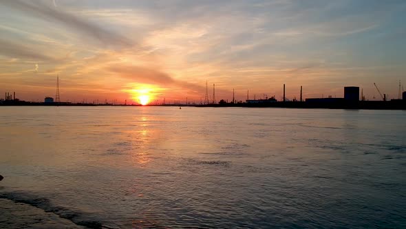 Antwerp International Port. Dramatic sunset over the river. Drone dolly out shot.