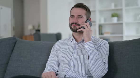 Cheerful Young Man Talking on Smart Phone at Home