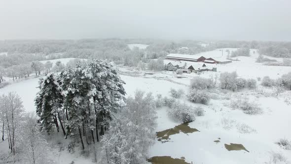 Aerial: Snow-covered stud farm in the wintertime