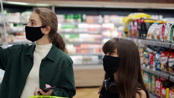 A Woman is Talking on the Phone and at the Same Time Taking Juice on the Shelf for Her Daughter