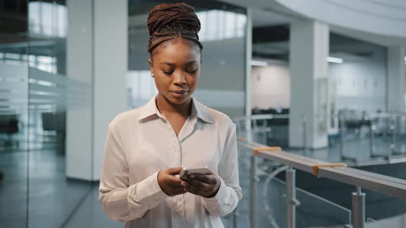 African Serious Focused Female Office Manager Woman Boss Leader with Modern Smartphone in Office