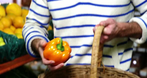 Man with a baskets selecting bell pepper in organic section