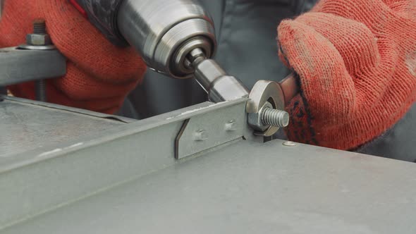 Closeup Worker Locksmith Tightens Nut with Screwdriver Closeup. The Master Tightens a Nut Metal