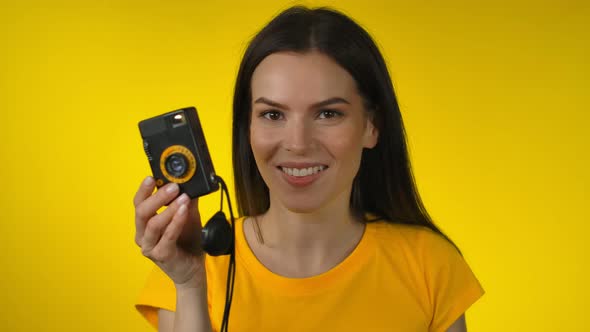 A Young Darkhaired Woman is Using a Retro Camera for Shooting a Picture