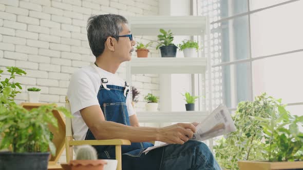 Holiday concept. An old asian man reading newspaper in the garden room. 4k Resolution.