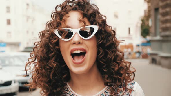 Beautiful smiling model with afro curls hairstyle dressed in summer hipster white dress