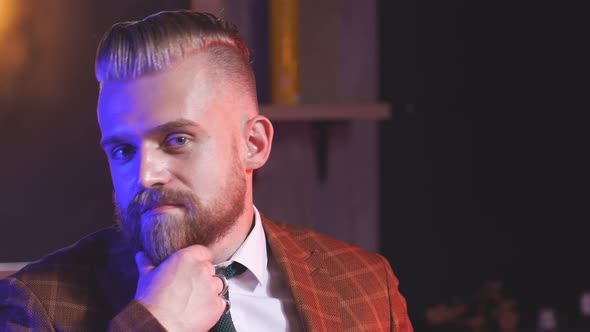 Brutal Male Client in Barbershop Sitting in Chair and Posing for Camera