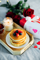 Mother's Day concept. Pancakes with berry, tea cup, burning candle, flowers and gift box. - PhotoDune Item for Sale
