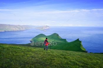 Tourist walks on Mykines with views of islands of Tindholmur and Vagar, Faroe