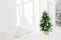 Decorated festive Christmas tree in white classic bedroom interior with soft bed. Winter home interi - PhotoDune Item for Sale