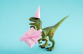 Cute green dinosaur with gift box and party hat on a blue background. Cute minimal birthday concept. - PhotoDune Item for Sale