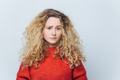 displeased unhappy young woman with curly bushy blonde hair, frowns face in bewilderment - PhotoDune Item for Sale