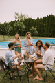 Group of young people cheering with cider by the pool in the garden - PhotoDune Item for Sale