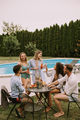 Group of young people cheering with cider by the pool in the garden - PhotoDune Item for Sale