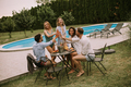 Group of young people cheering with cider by the pool in the garden - PhotoDune Item for Sale