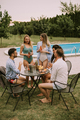 Group of young people cheering with cider by the pool in the garden - PhotoDune Item for Sale