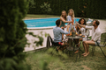 Group of young people cheering with cider by the pool in the garden - PhotoDune Item for Sale