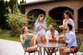 Group of young people cheering with cider and eating pizza by the pool in the garden - PhotoDune Item for Sale