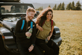 Smiling couple preparing hiking adventure with backpacks by terrain vehicle - PhotoDune Item for Sale
