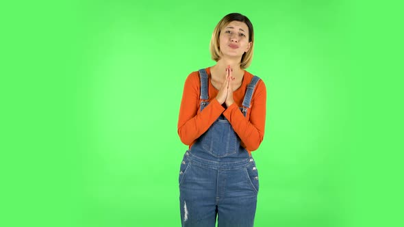 Girl Looks with Tenderness with Folded Arms in Front of Her. Green Screen