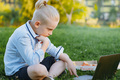 cute caucasian boy sitting on grassin park with laptop computer. - PhotoDune Item for Sale