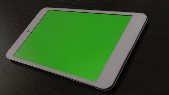 Greenscreen tablet display on dark wooden surface slow pan 4K 3840X2160 UHD video - Silver white mod