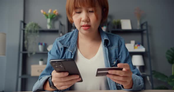 Young asia lady use cellphone order online shopping product and paying bills with credit card.