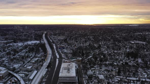 An aerial shot in the suburbs with train tracks and a highway. It was shot at sunrise after a snow s