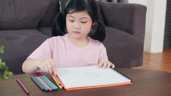 Young Asian girl drawing relax rest fun happy draw cartoon in sketchbook.