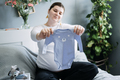 Pregnant woman with big belly holding bodysuit and sorting clothes for future. How to Organize - PhotoDune Item for Sale