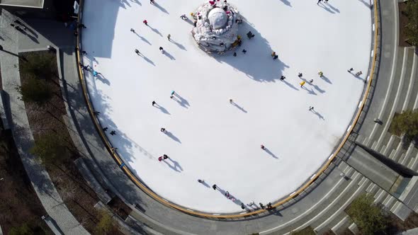 Many People are Skating on White Outdoor Ice Rink in City on Sunny Winter Day