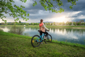 Woman riding a mountain bike near lake and blue sky in spring - PhotoDune Item for Sale
