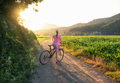 Woman on mountain bike on gravel road at sunset in summer - PhotoDune Item for Sale
