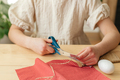 A girl at home makes Easter egg decorations in the shape of a rabbit from fabric. The child cuts the - PhotoDune Item for Sale