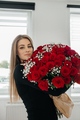 Charming young woman with a huge bouquet of red roses. Flower delivery for holidays - PhotoDune Item for Sale