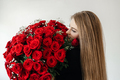 A young girl with a huge bouquet of red roses. Happy woman smelling flowers. Gifts for holidays - PhotoDune Item for Sale