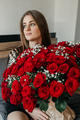 Charming young woman with a huge bouquet of red roses. Flower delivery for holidays  - PhotoDune Item for Sale