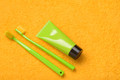 Green toothbrushes with paste tube on yellow bath towel. Visual representation for dental clinics - PhotoDune Item for Sale