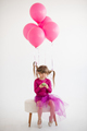 Funny kid girl celebrating birthday with balloons in room over white - PhotoDune Item for Sale