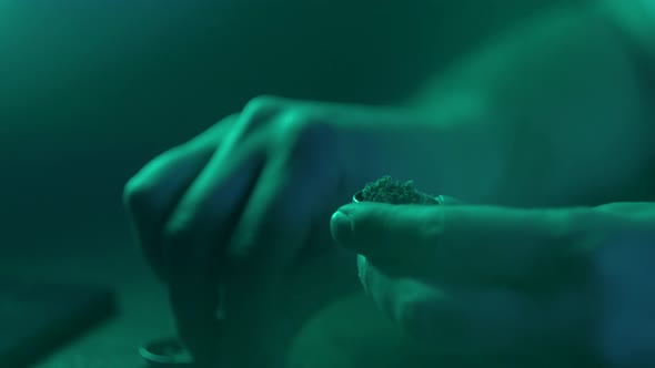 Man Rolling a Medical Marijuana Joint in Night Club. Close Up of Addict Marijuana Joint with Lighter