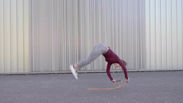 Young woman skipping rope and cartwheeling in the street