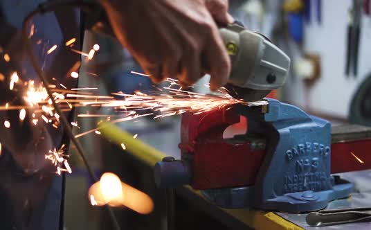 Worker Man Making Sparks While Grinds with Electric Saw