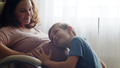Child hugs her mother's pregnant belly. Happy son strokes the big belly his pregnant mom near window - PhotoDune Item for Sale