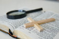 Open Holy Bible with a cross and magnifying glass. The concept of Bible learning. - PhotoDune Item for Sale
